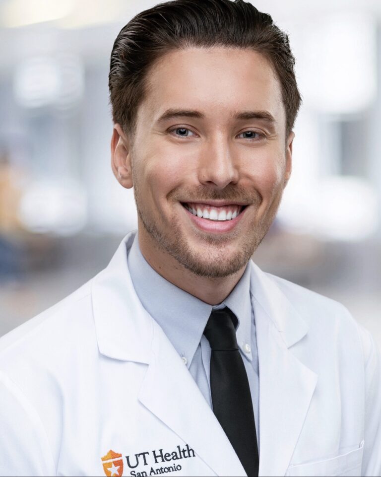 Smiling male dentist in a white coat at DTX Dental Studio in Dallas, Texas.