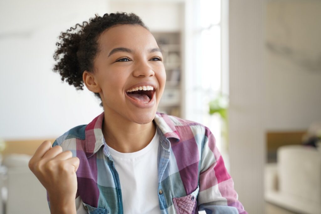 excited mixed race teen girl makes yes winner hand